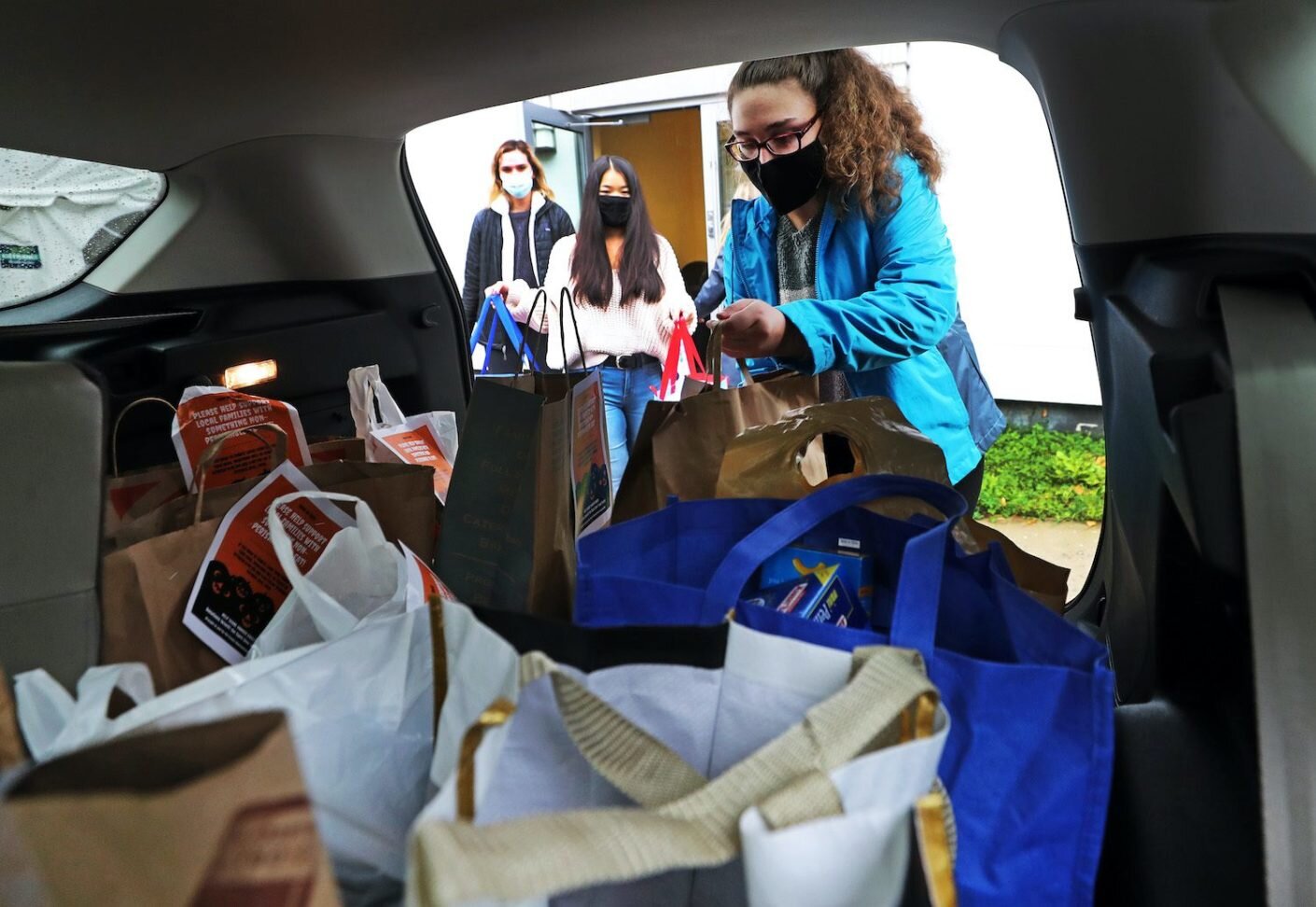 Endicott College student Grace Vartanian, right, and other students load donated food that they have collected into the back of a car for transport in Beverly, Massachusetts.